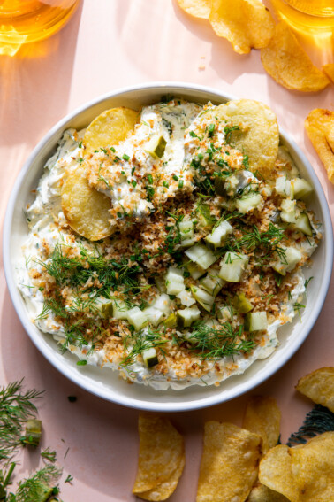 Bowl of dill pickle dip topped with toasted pinko, fresh dill and chives.