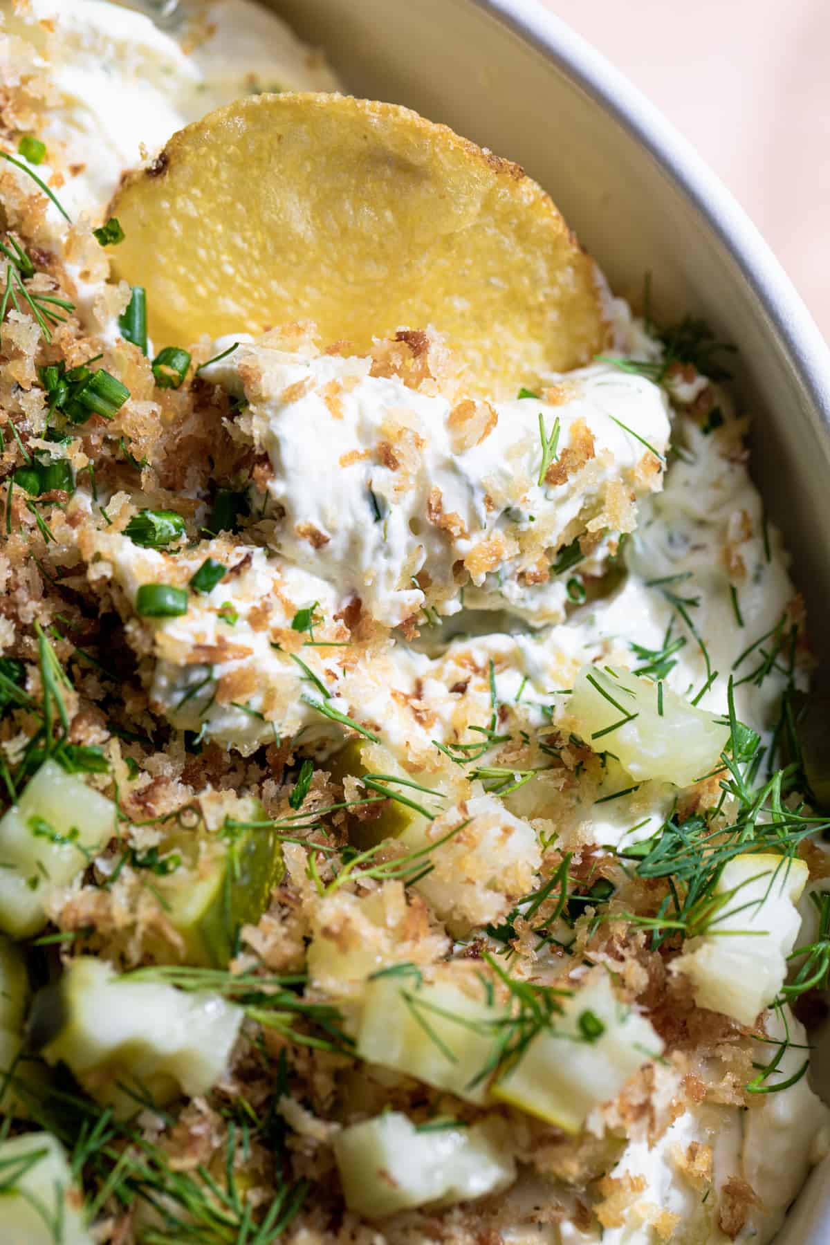 Potato chip scooping up a creamy fried pickle and ranch dip.