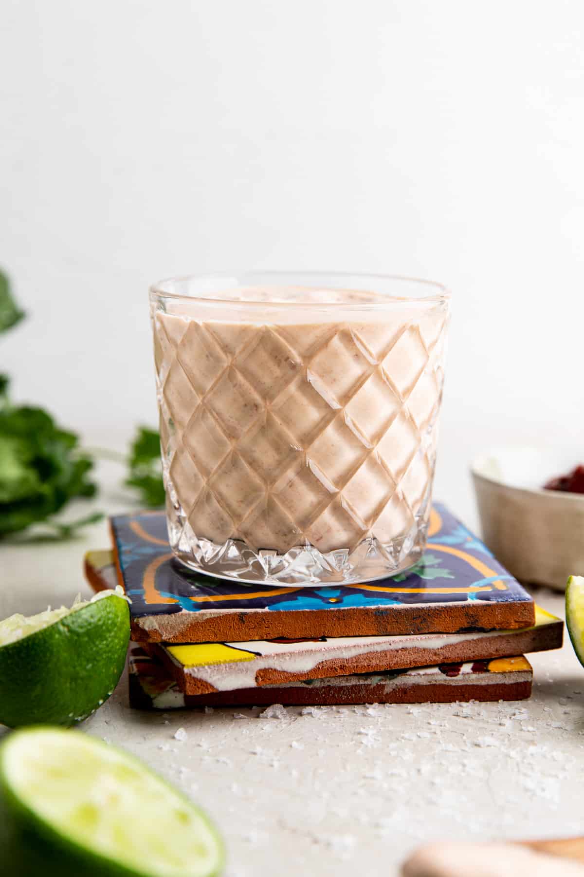 Chipotle crema in a glass on a stack of mexican tiles. 