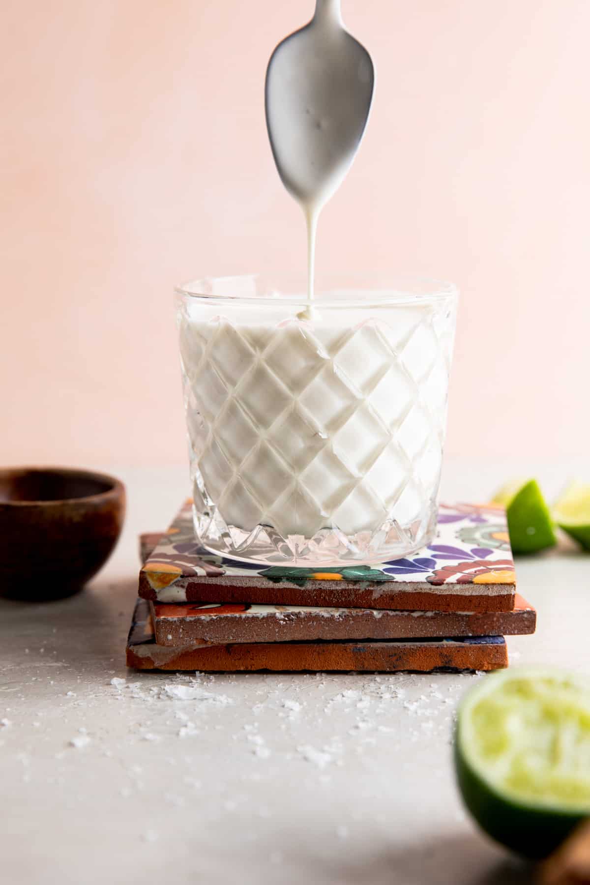 Cup filled with homemade mexican crema with a spoon above drizzling crema.
