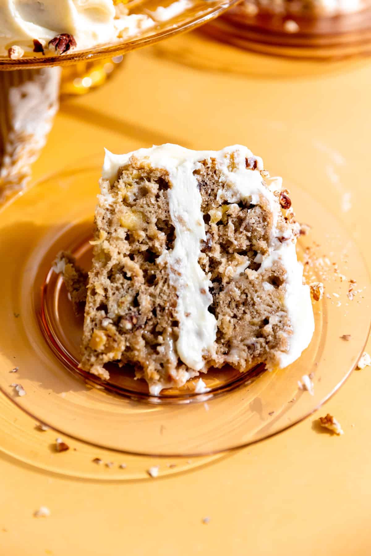 A slice of hummingbird cake on a glass orange plate.