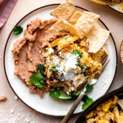 Plate with refried beans, and scrambled egg mias with tortillas chips, topped with queso fresco and fresh cilantro.