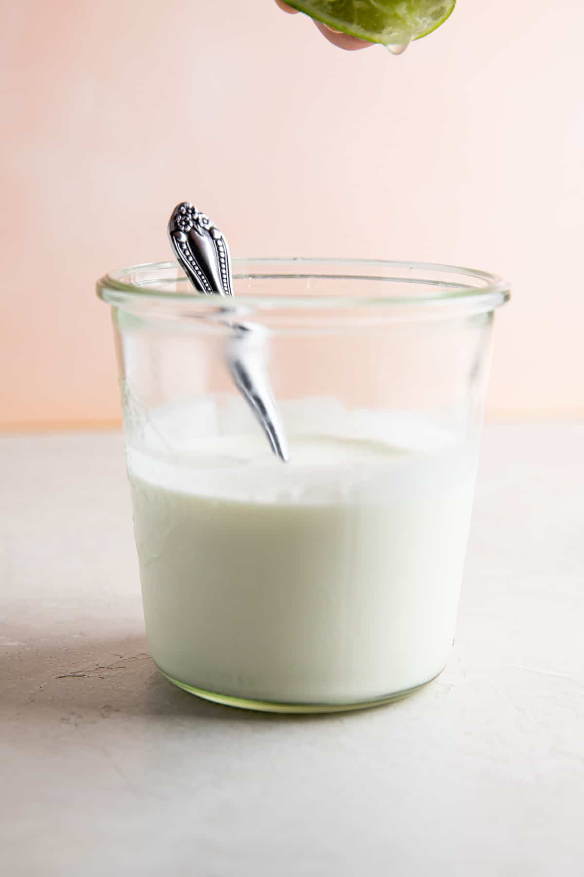 Squeezing lime juice into a jar filled with Mexican sour cream.