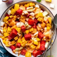 Bowl filled with mexican fruits, topped with tajin and drizzled with chamoy.
