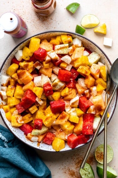 Bowl filled with mexican fruits, topped with tajin and drizzled with chamoy.