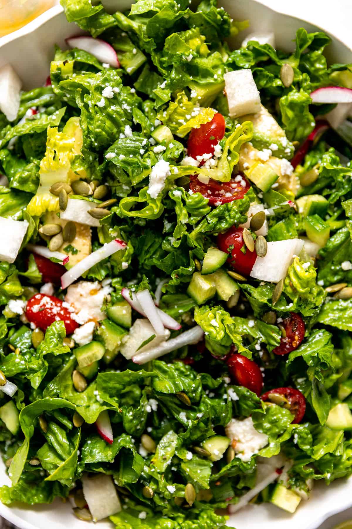 Up close of a salad mixed with dressing in a white bowl. 