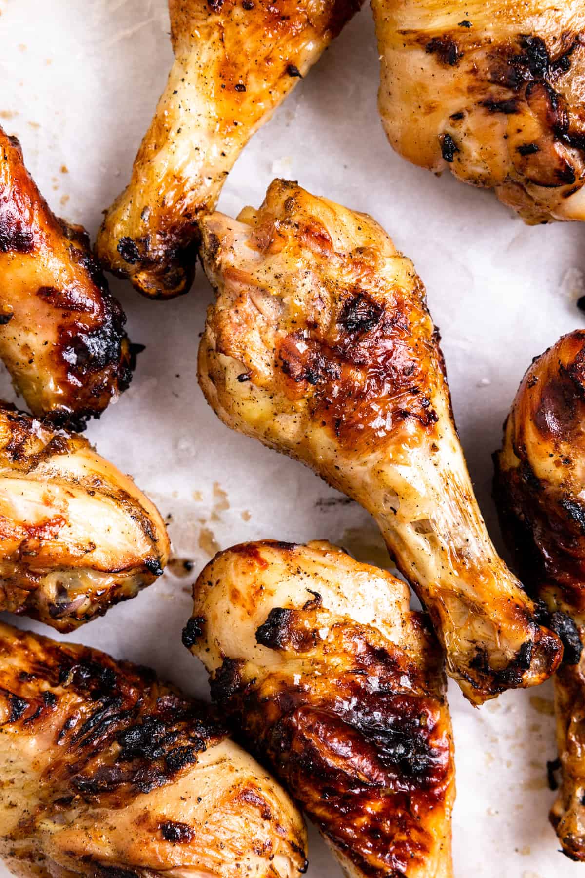Grilled chicken drumsticks on white parchment paper.