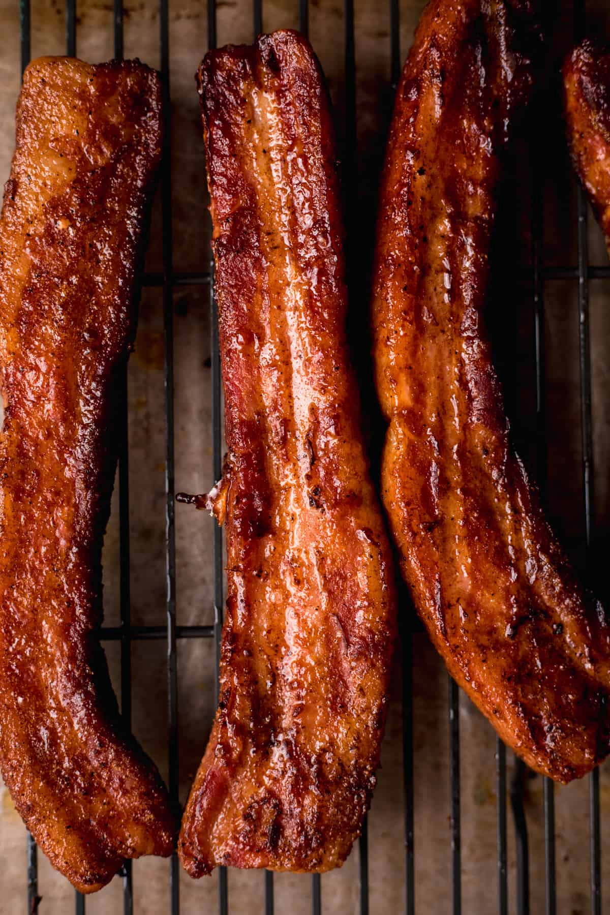 Strips of smoked pork belly on a black wire grate.
