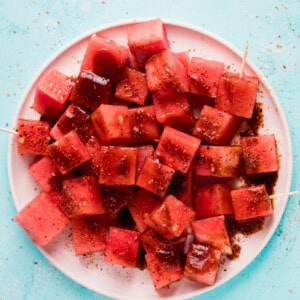 Overhead view of white plate with cubed watermelon and tajin with chamoy.