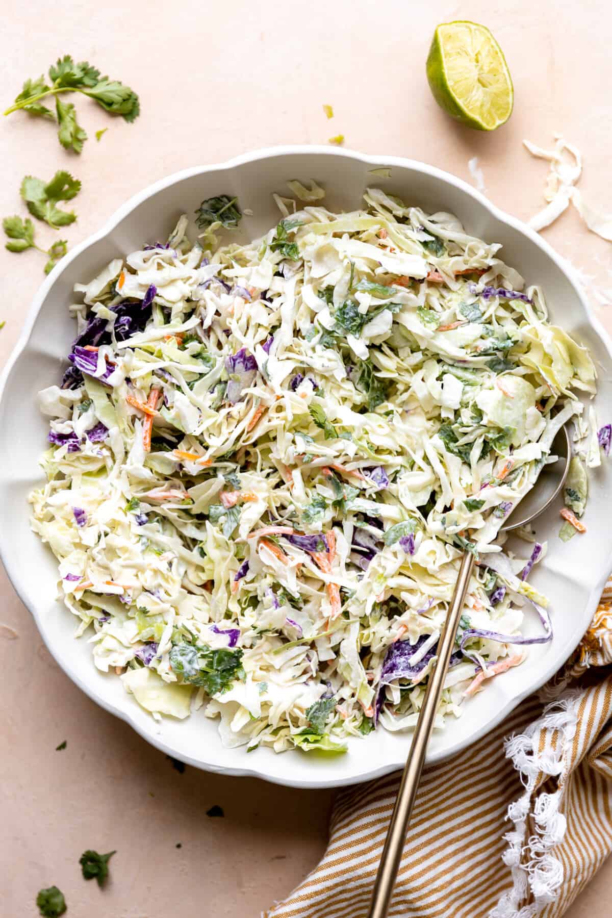 White bowl with creamy fish taco slaw made with red and green cabbage.