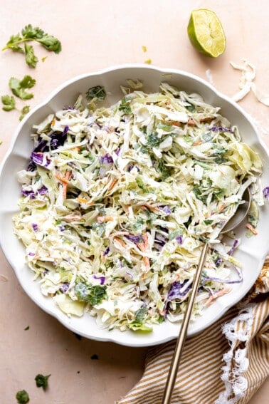 White bowl with creamy fish taco slaw made with red and green cabbage.