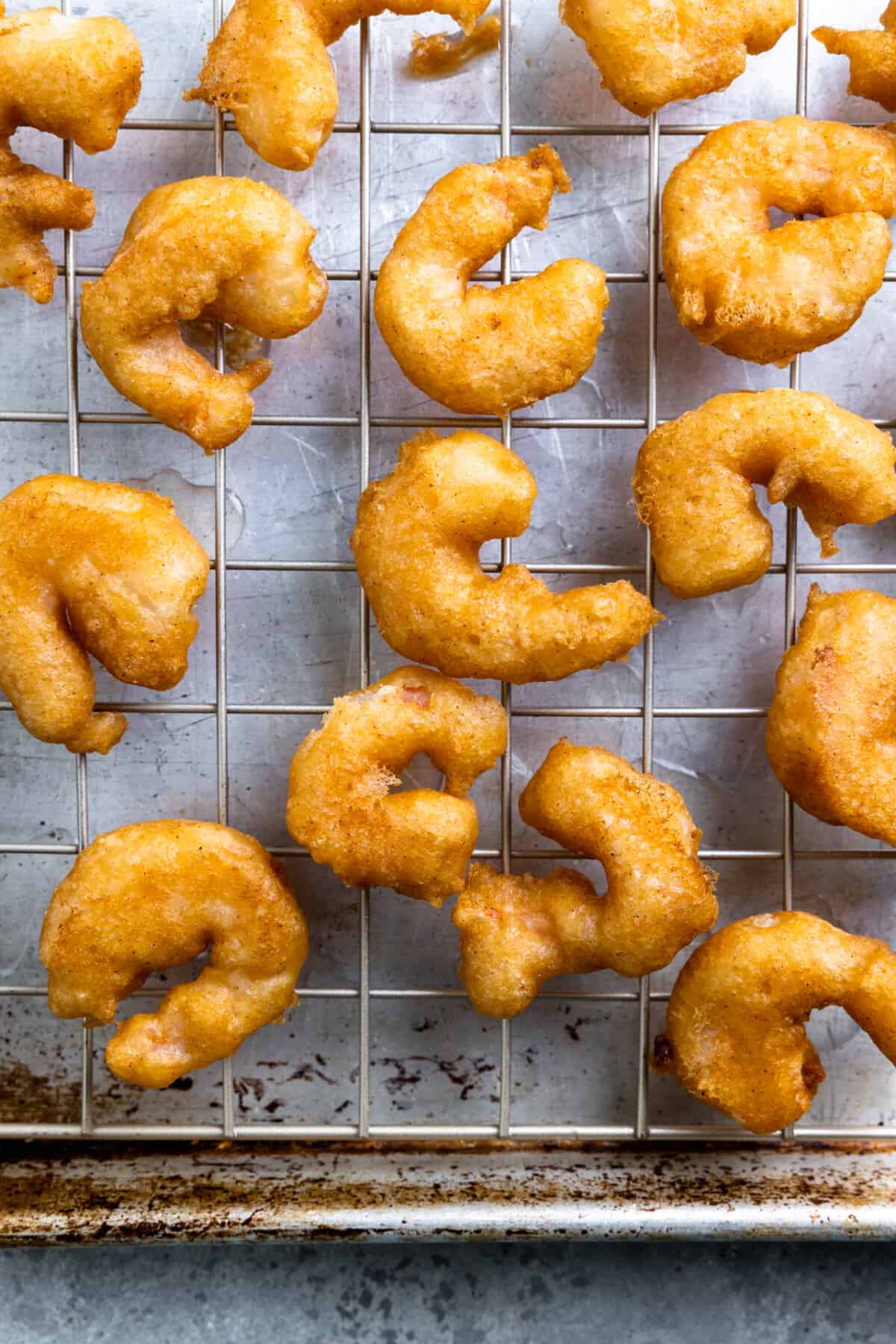Fried shrimp on a wire rack placed on a baking sheet.