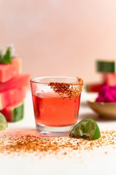 Shot glass filled with Mexican Candy shot. Slices of watermelon on the side.