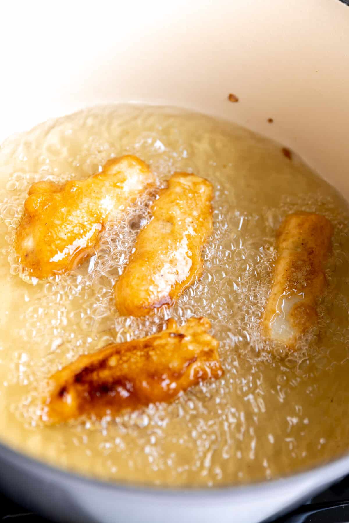 Beer battered mahi mahi frying in a dutch oven with oil. 