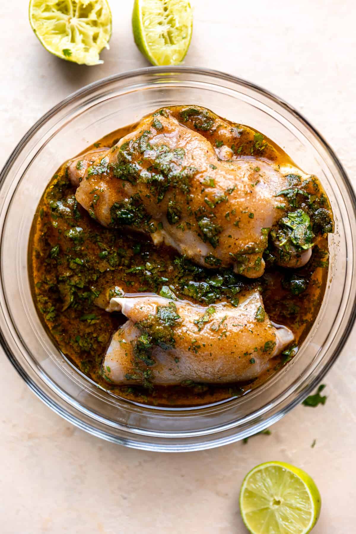 Chicken thighs marinating in a mexican marinade in a glass bowl. 