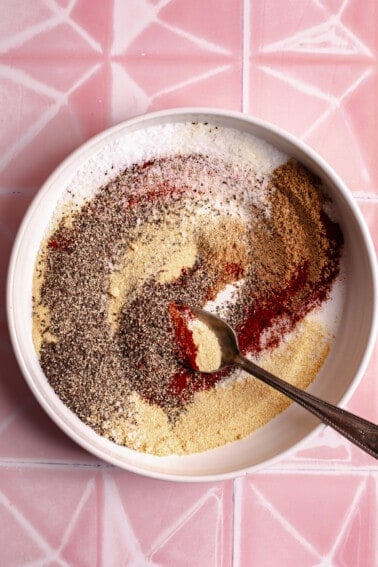 Plate with seasoning mix for a brisket rub and a spoon.
