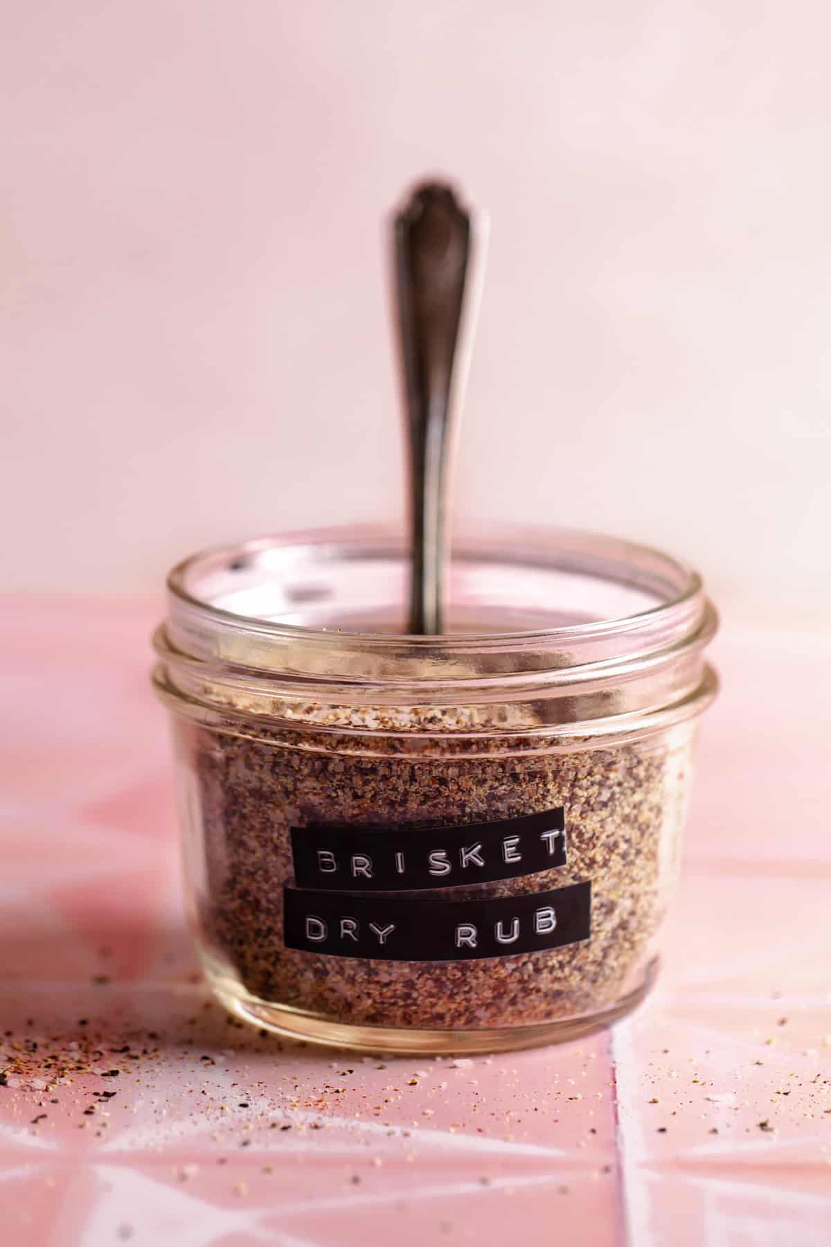 Small glass jar filled with spice mix and a label of Brisket Dry Rub.