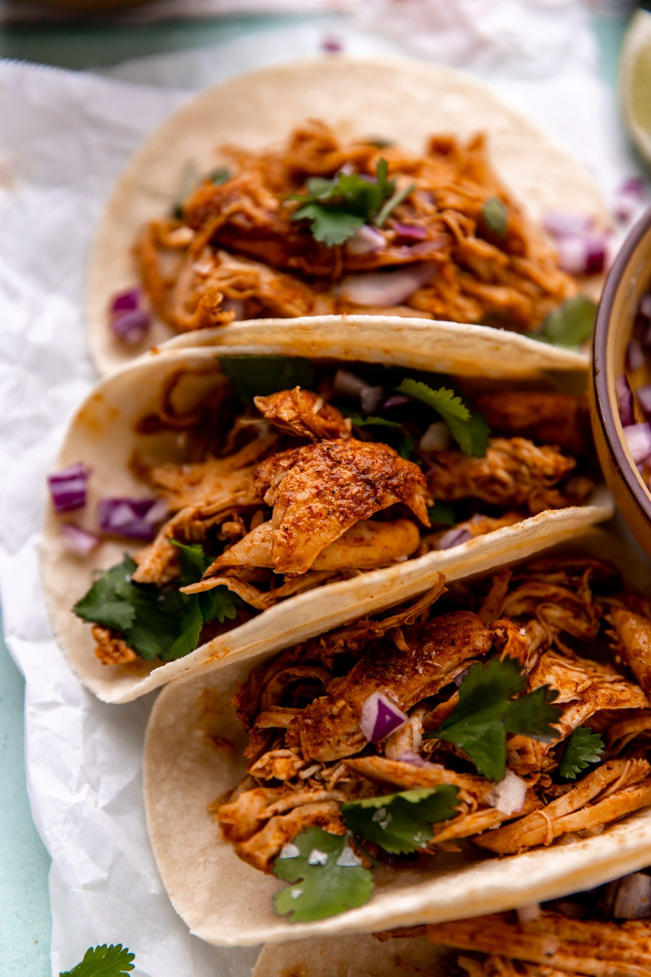 Shredded chicken on corn tortillas topped with red onion and cilantro. 