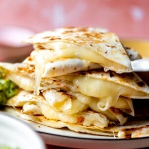 Stack of cheese quesadillas with melted cheese coming out the sides.