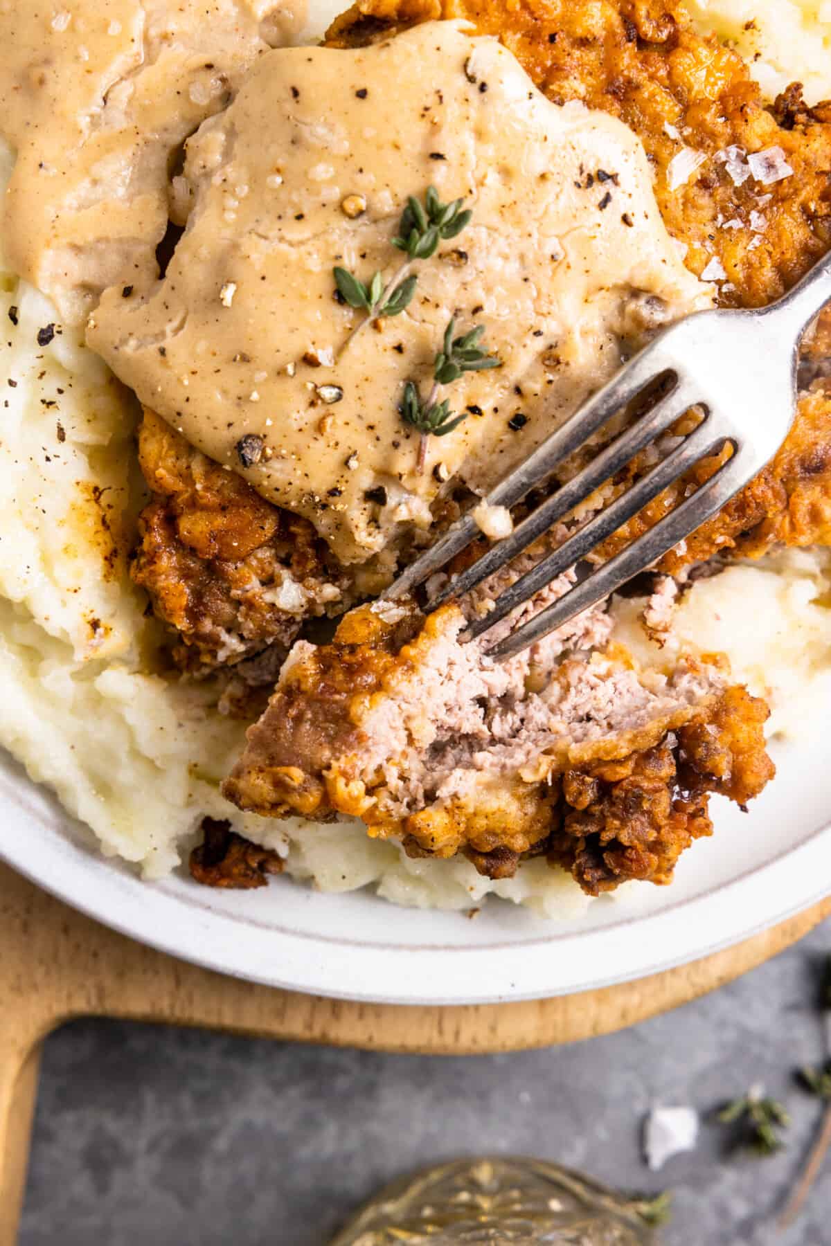 Up close of slice of chicken fried steak with cream gravy on top.