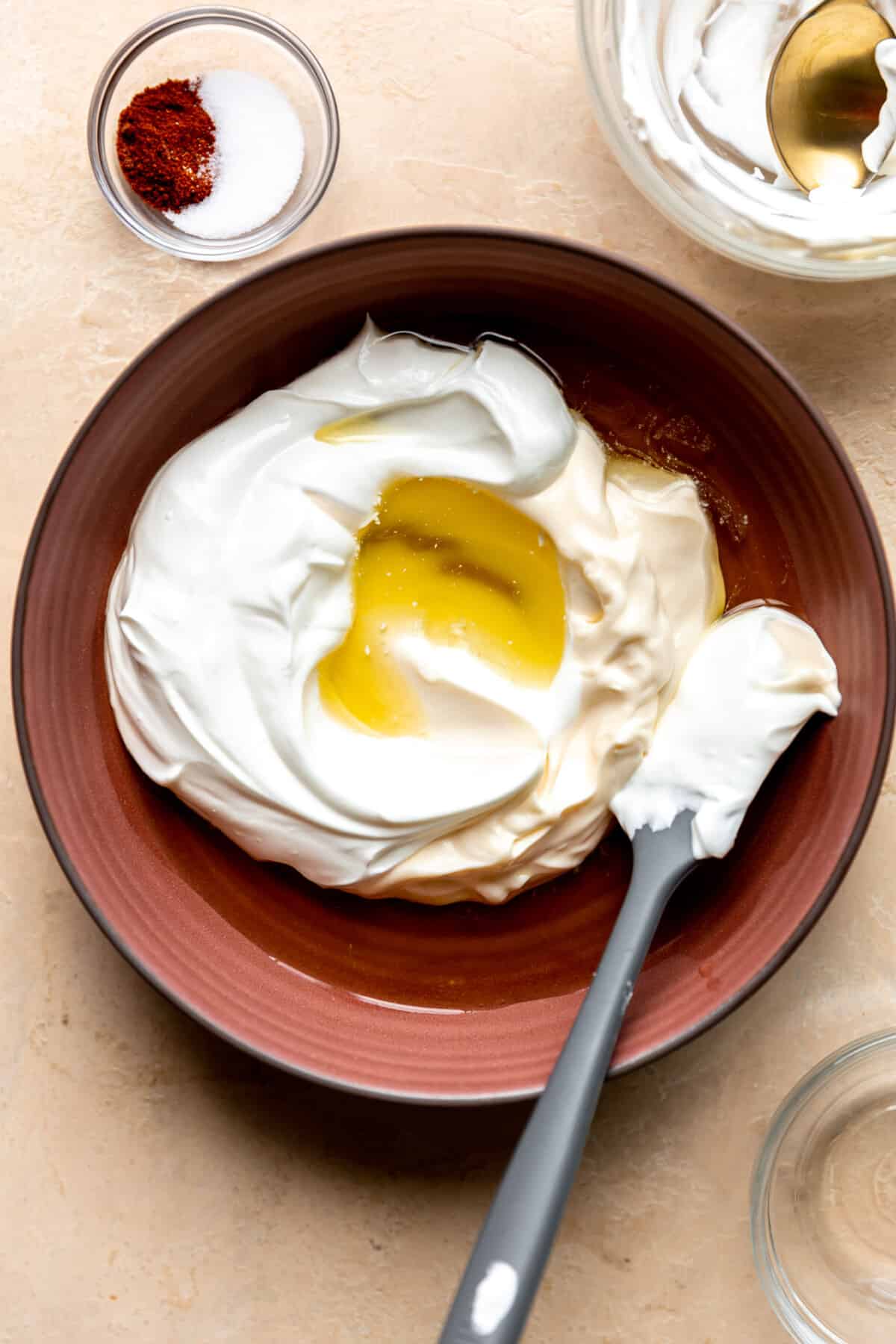 Bowl with mayonnaise and sour cream with jalapeño brine being added. 