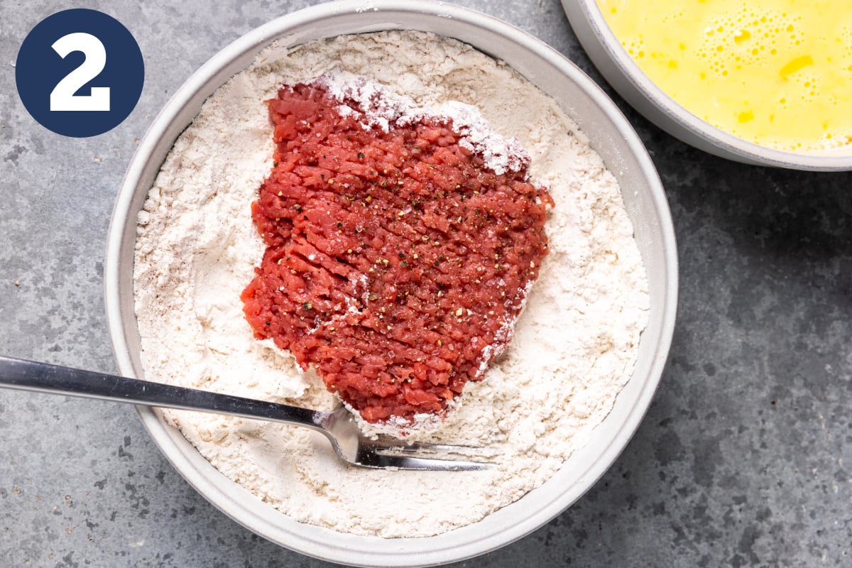 Cube steak in a bowl of flour. 