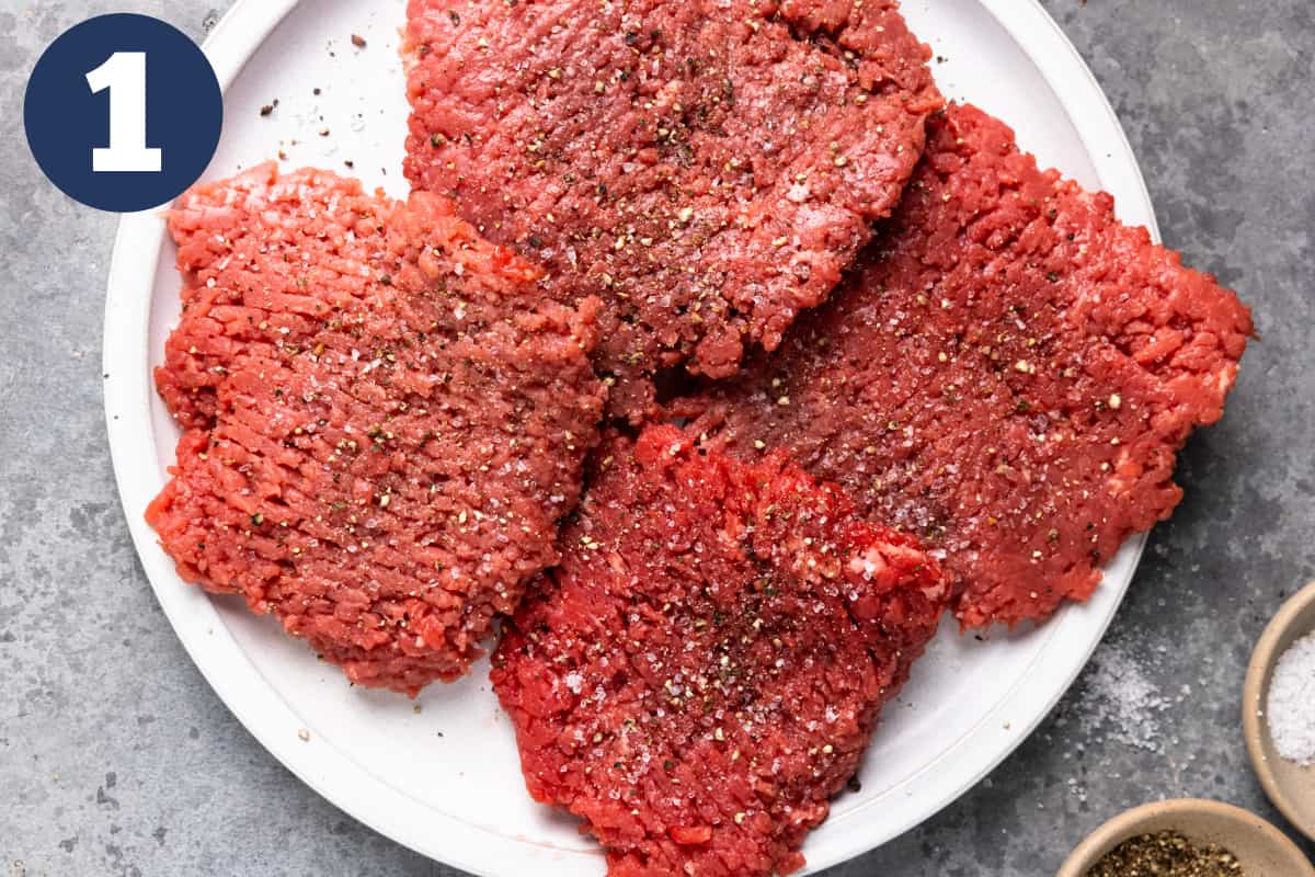 White plate with cube steaks covered in salt and pepper.