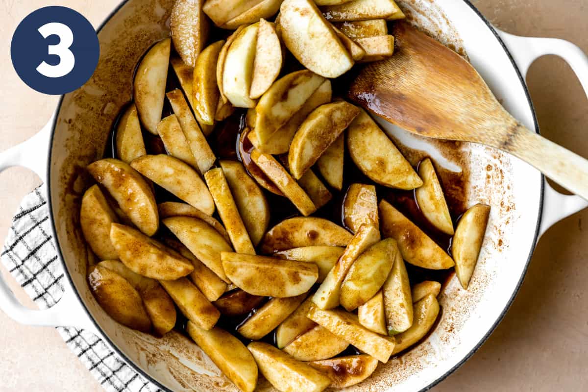 Apples being cooked in a skillet with melted butter and spices. 