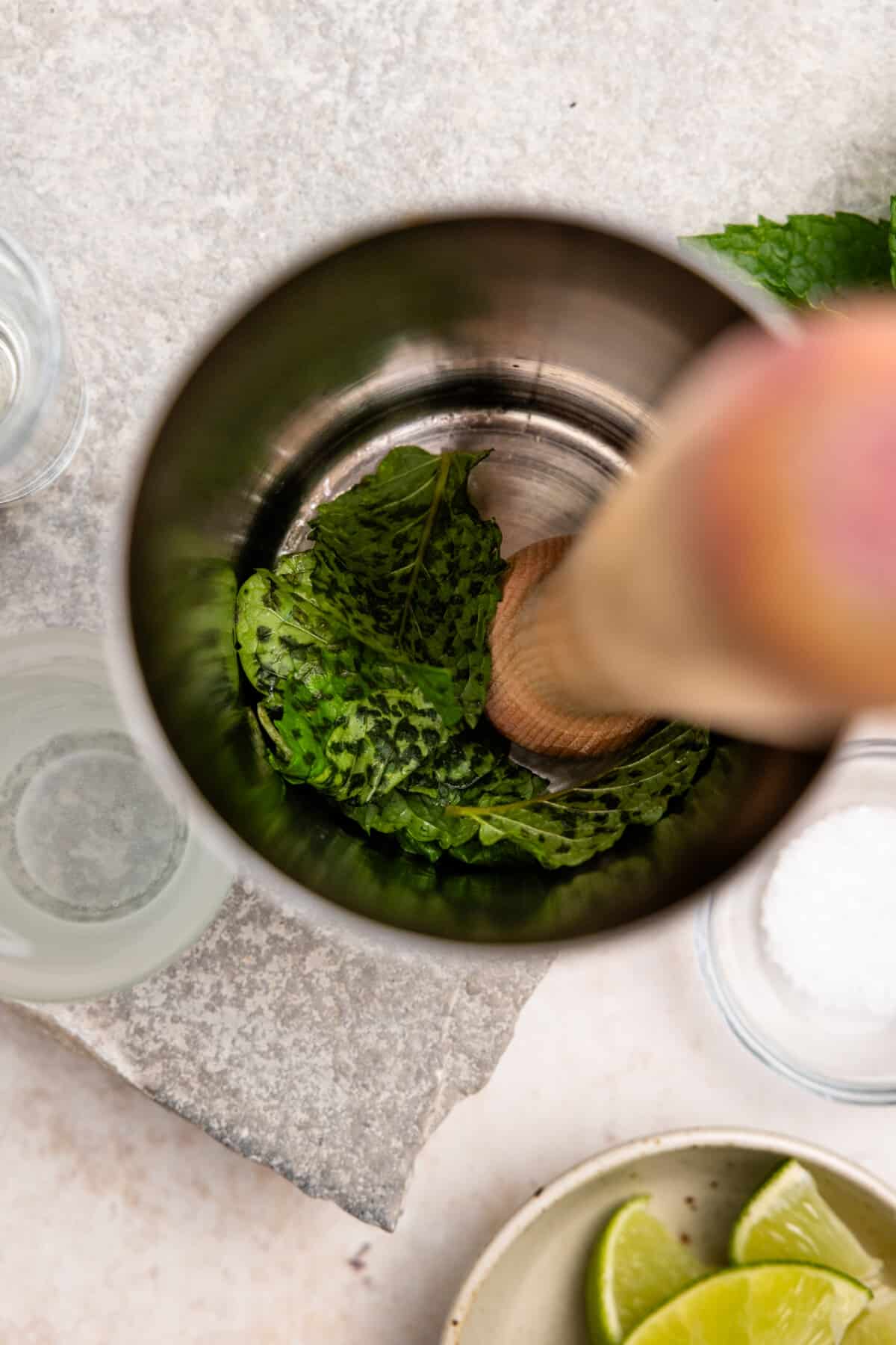 Muddling mint in a cocktail shaker.