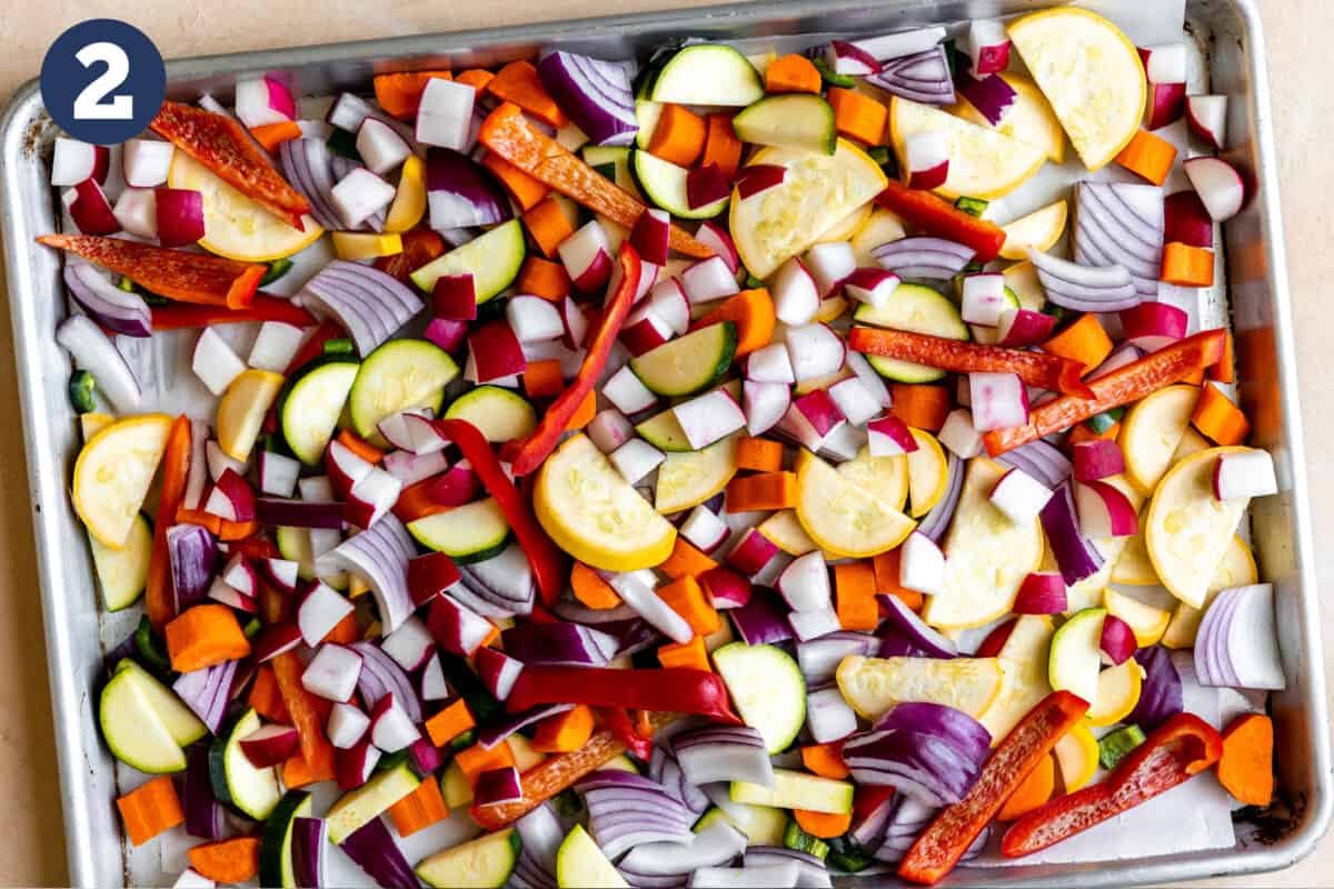 Sheet pan with raw chopped vegetables.