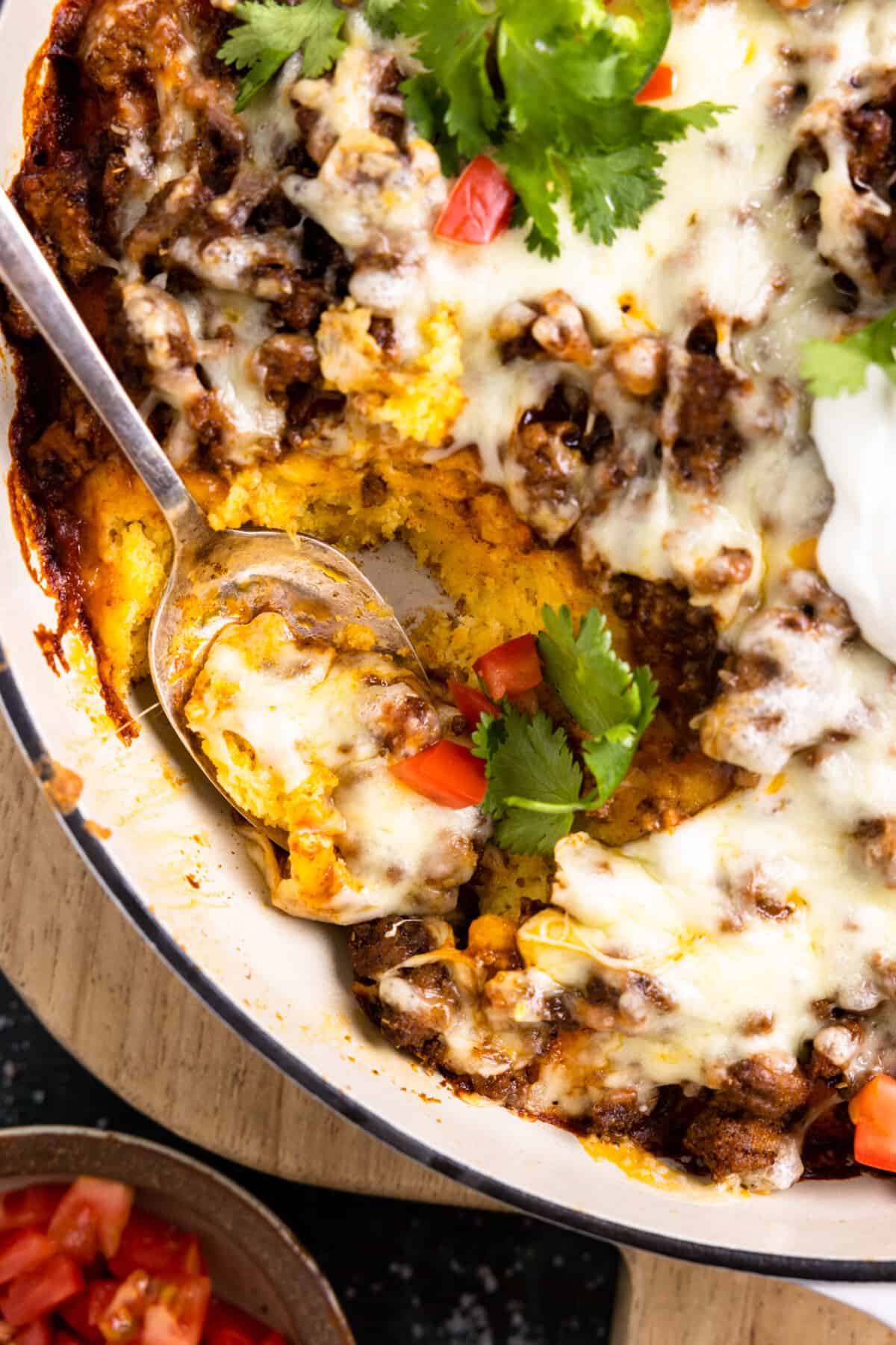 Spoon scooping up a serving of tamale pie from a baking dish. 