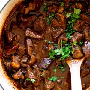 White dutch oven filled with carne guisada topped with fresh cilantro.