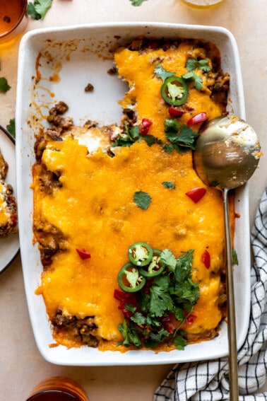 Baking dish with John Wayne Casserole with a portion served and a golden spoon on the side.