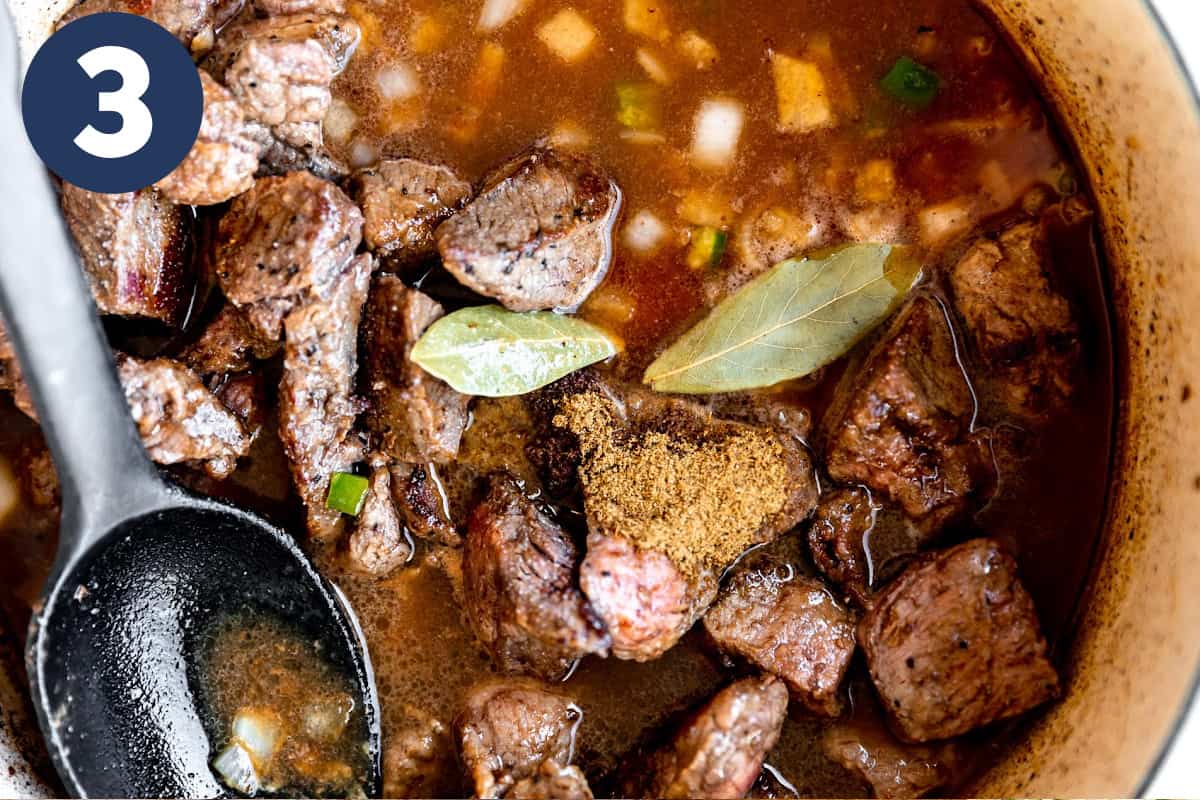Dutch oven with stew meat in broth with bay leaves ready to simmer. 