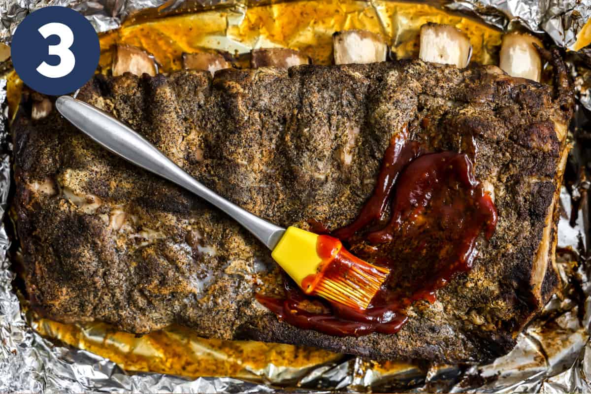 Brushing BBQ sauce on beef ribs being cooked in oven. 