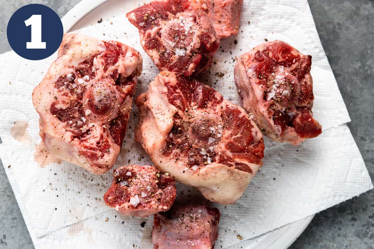 Oxtails on a paper towel sprinkled with salt and pepper. 