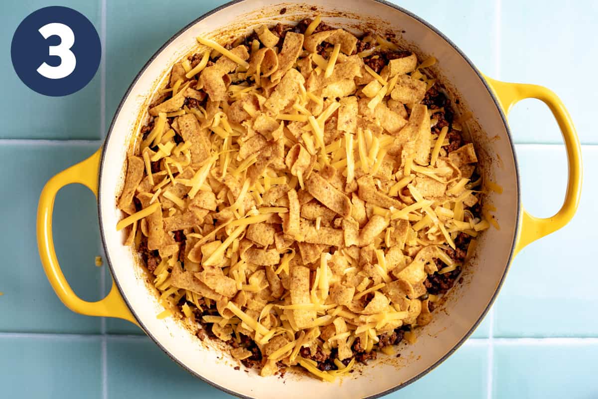 Taco meat and beans topped with cheese and corn chips ready to be baked. 