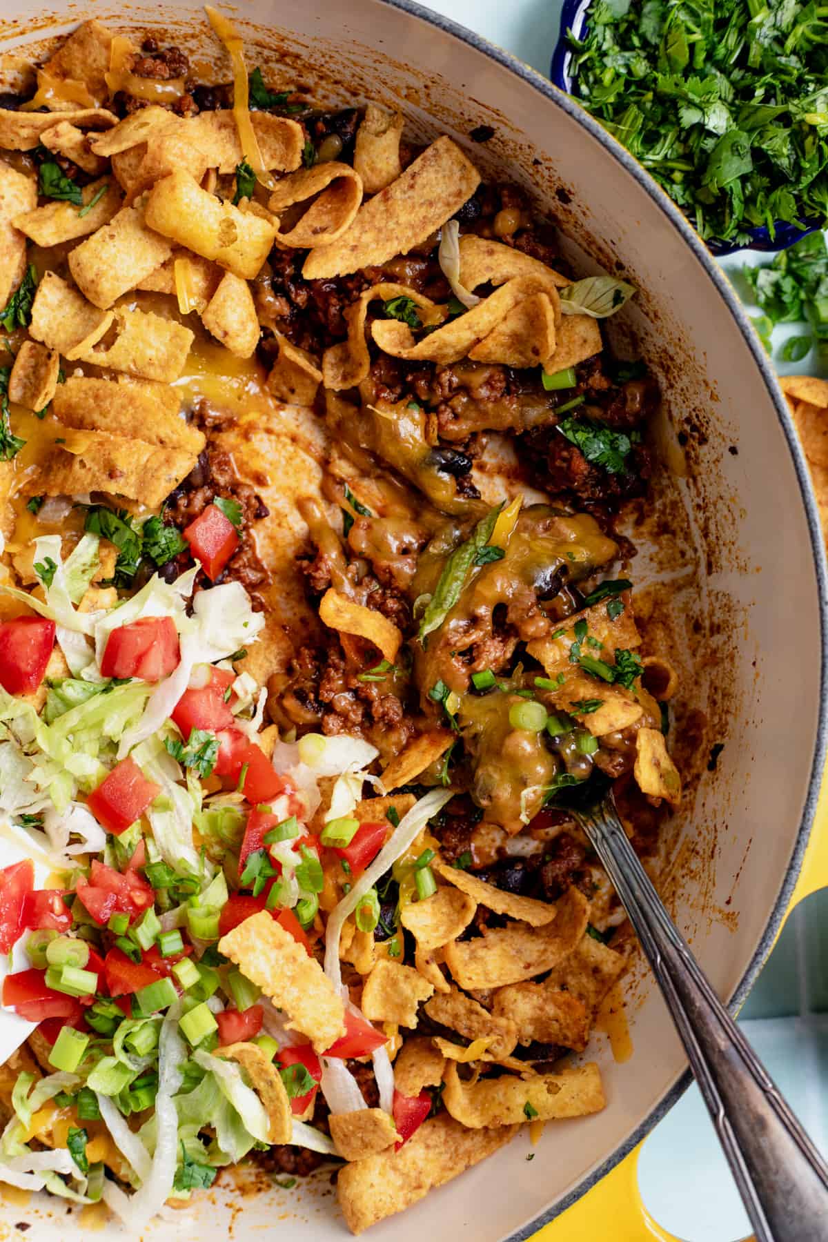 Up close spoon serving up walking taco casserole from a dish.