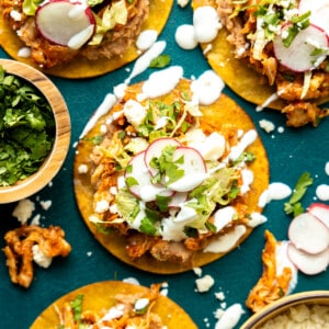 Tostadas topped with chicken tinga, drizzled with crema.