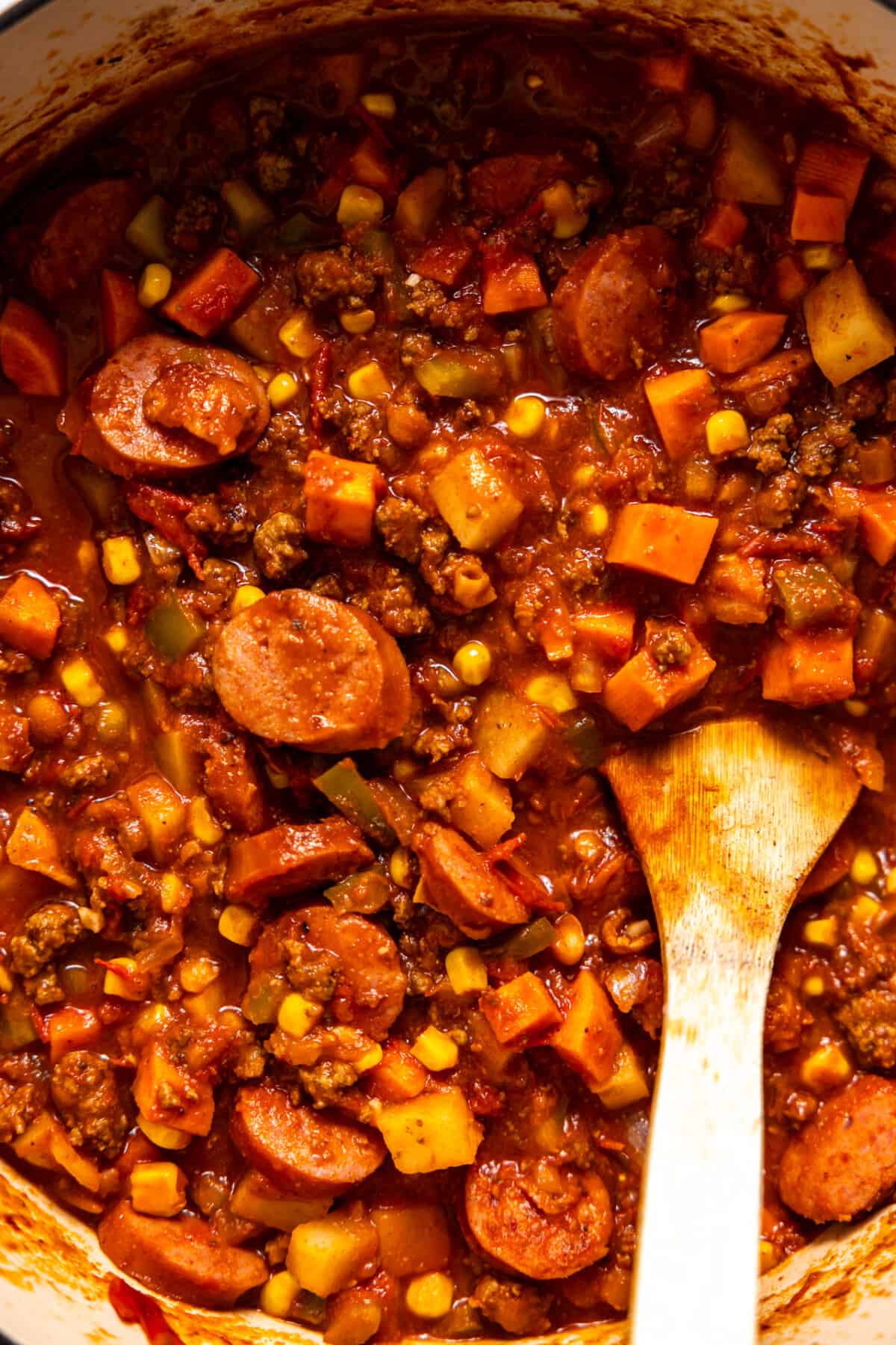 Pot of cooked cowboy stew with a wooden spoon to serve. 