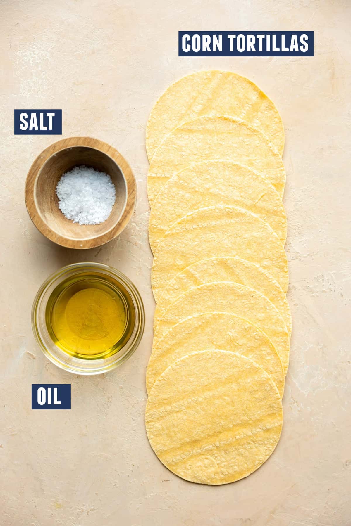 Ingredients needed to make homemade tostadas on the counter, corn tortillas, oil and salt. 