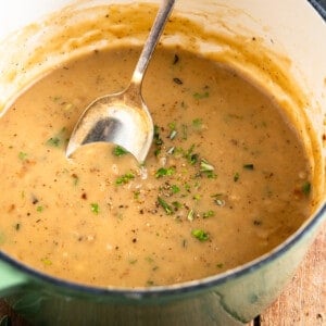 Dutch oven filled with gravy and topped with herbs.