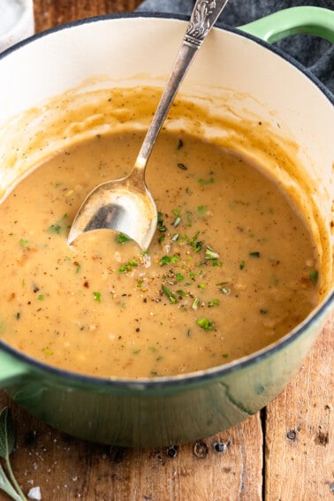 Dutch oven filled with gravy and topped with herbs.