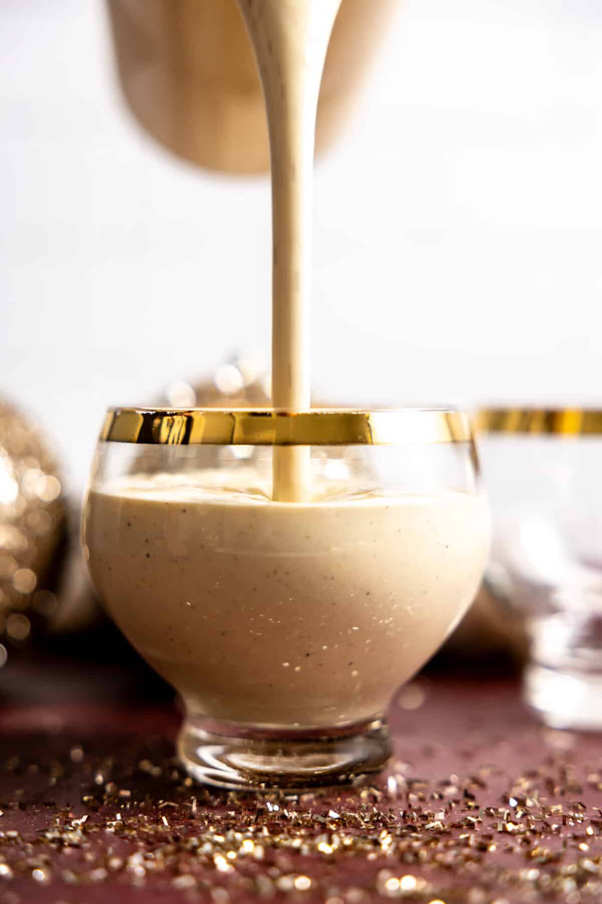 Pouring eggnog into a glass to serve.