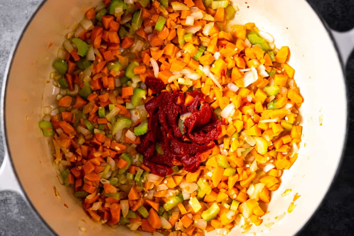 Sauted vegetables in a braising pan with tomato paste added. 