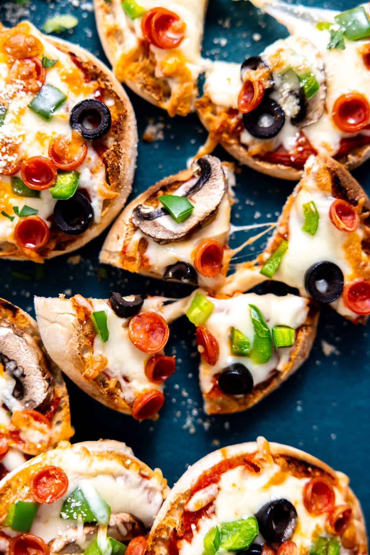 Sliced English muffin pizza with cheese pull. 