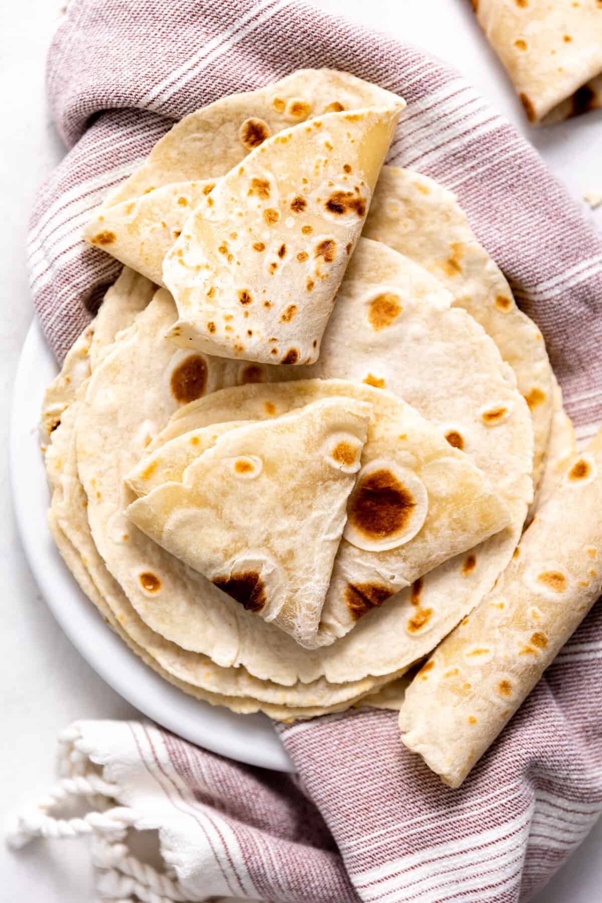 Plate filled with homemade flour tortillas. 