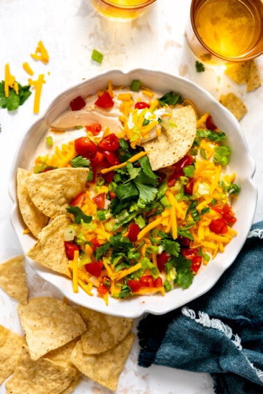 Taco dip in a white dish served with tortilla chips.