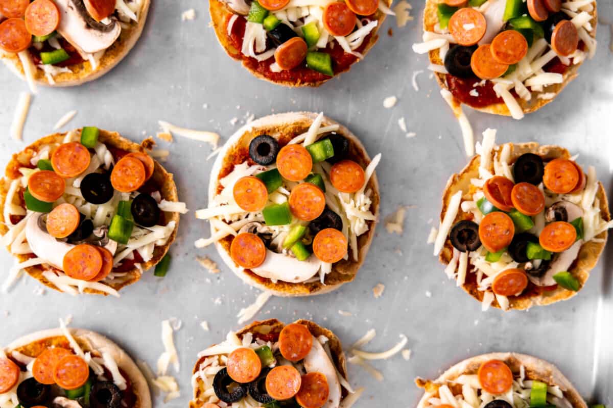 Pizza toppings added to English muffin pizzas before baking.