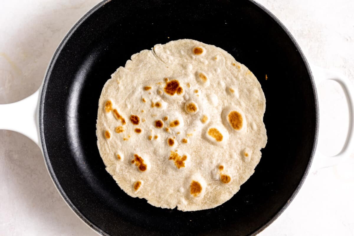 A flour tortilla being cooked in a skillet. 